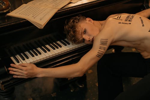 Free A Topless man Leaning on a Piano Stock Photo