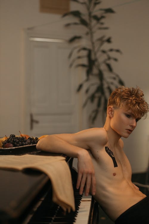 A Shirtless Man Leaning Back on a Piano