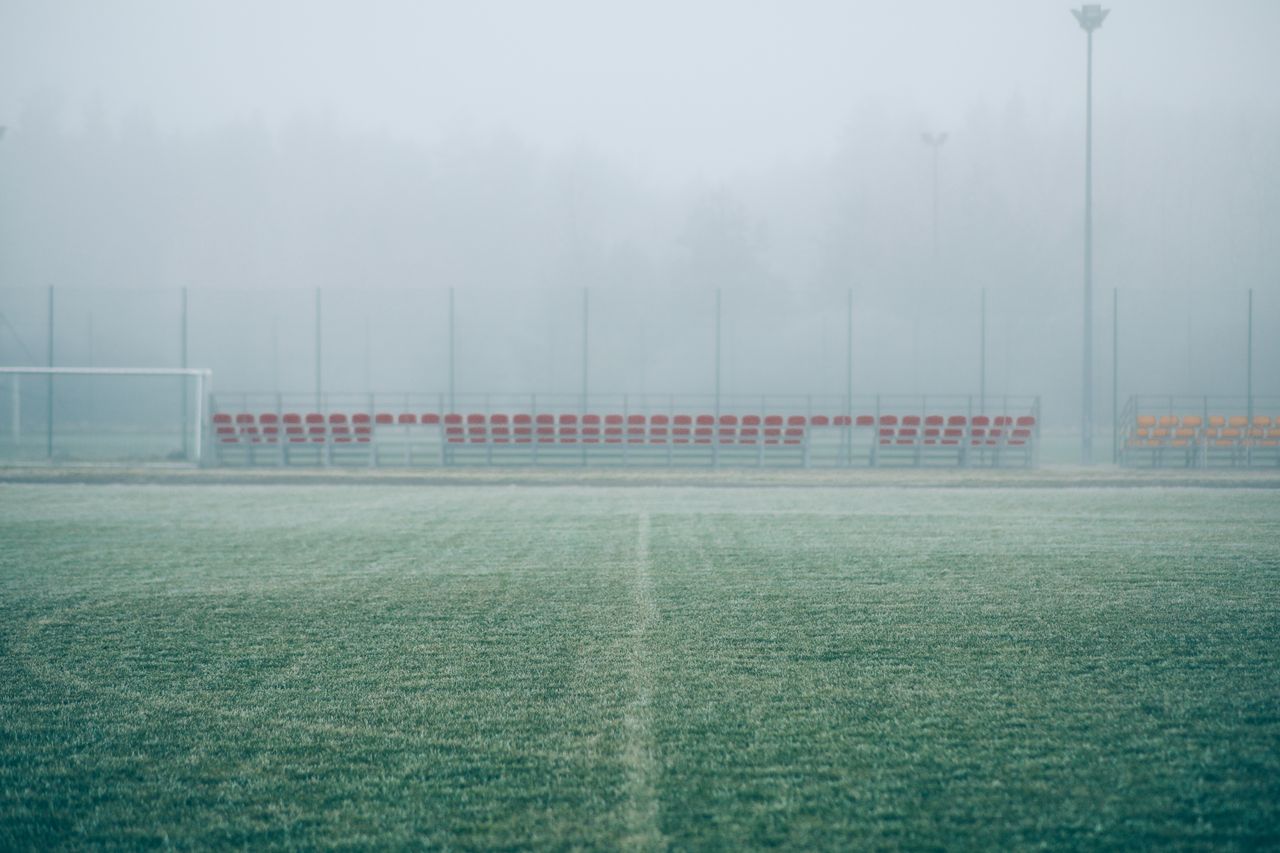 foggy soccer field with empty bleachers creating a serene and mysterio