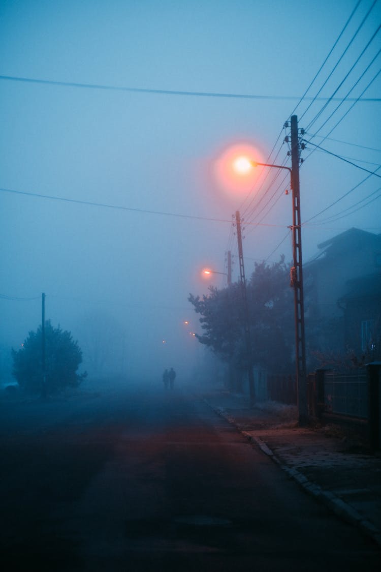 Silhouette Of People Walking On A Foggy Road 