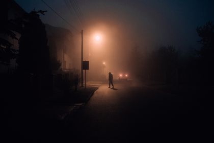 A lone silhouette on a foggy street at night under lamplight — photo by KoolShooters on Pexels