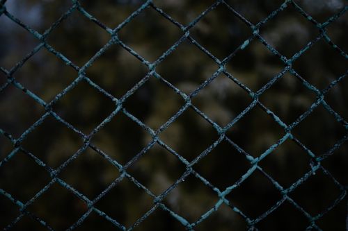 Free Close-up of a rusty chain link fence with a blurred natural background in daylight. Stock Photo