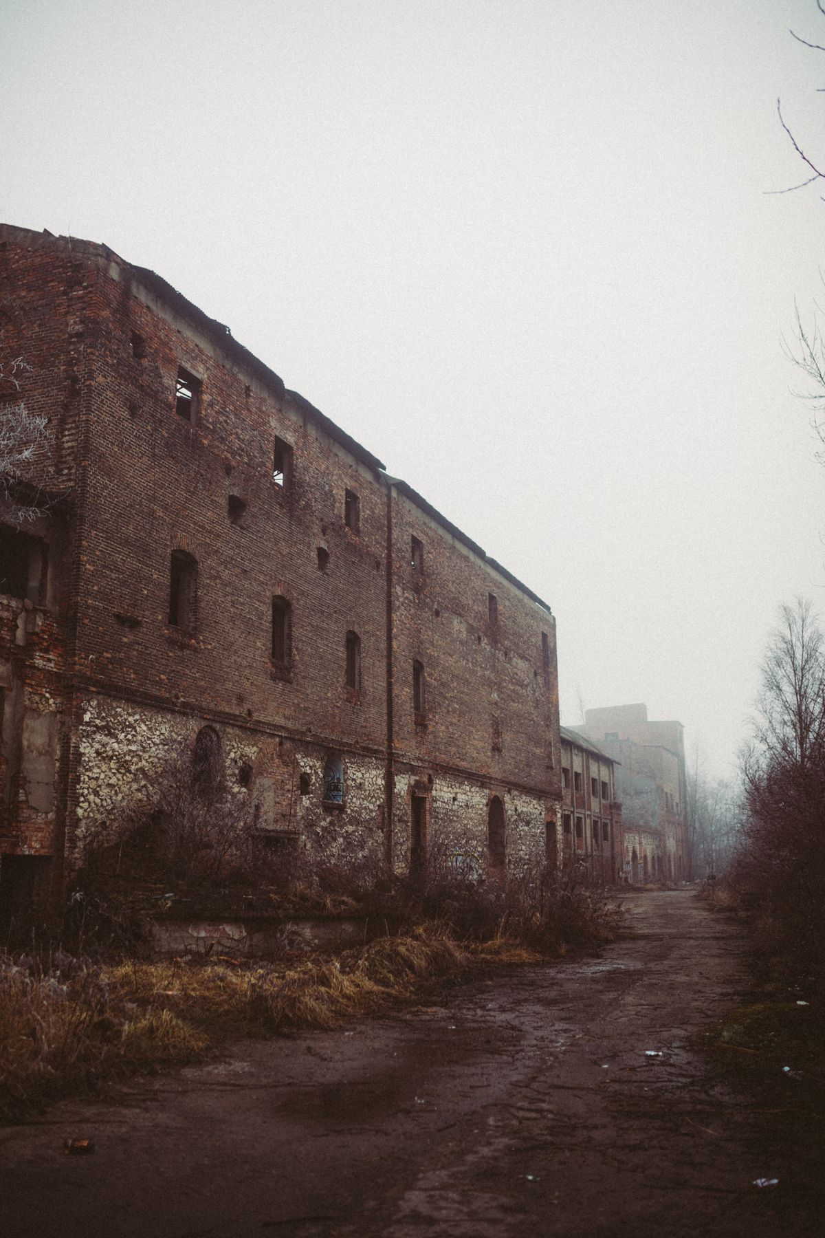 A dilapidated brick warehouse on a foggy winter day showing urban decay, evoking Hashima in poor weather