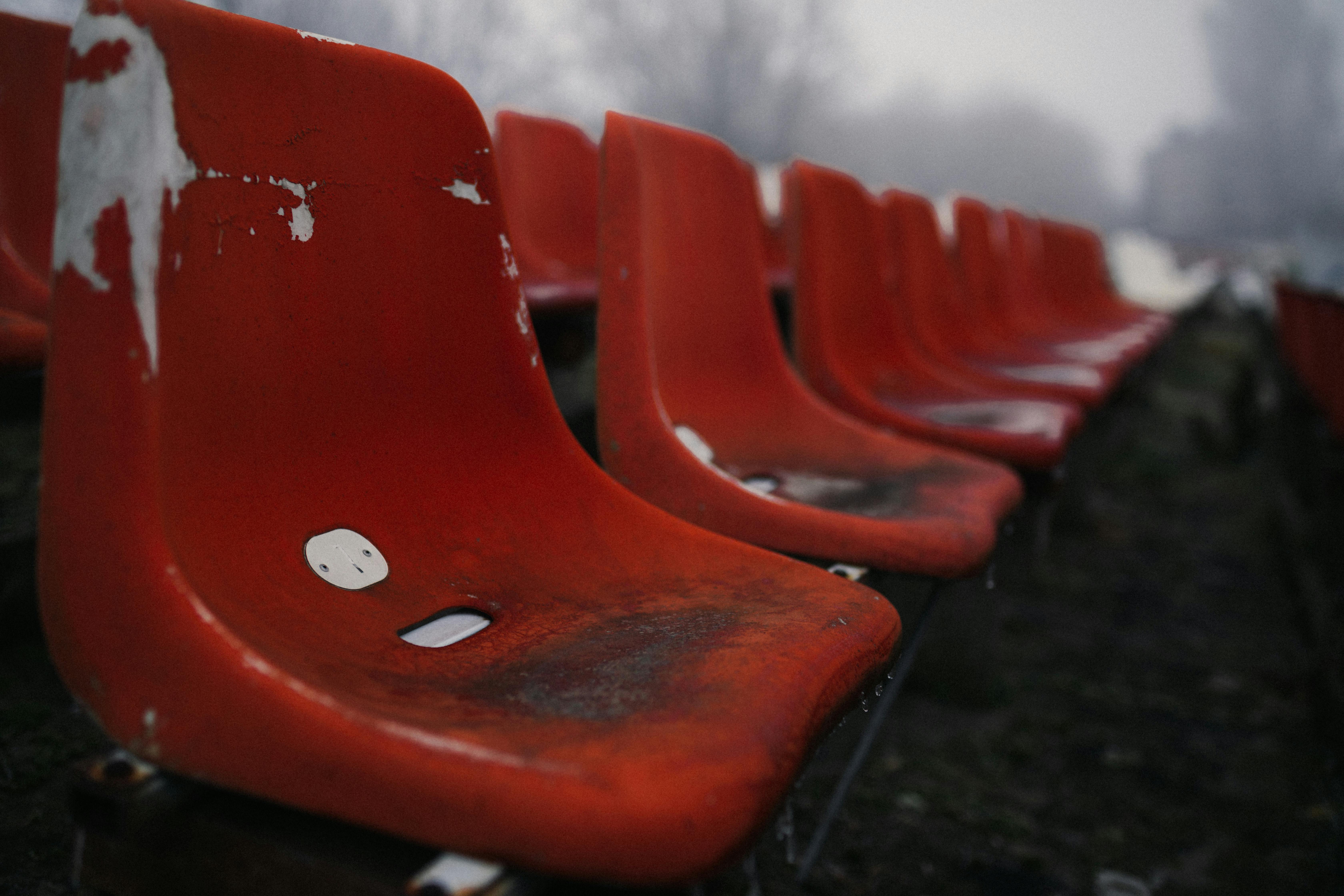 Close-up of weathered red stadium seats, empty and abandoned in winter.