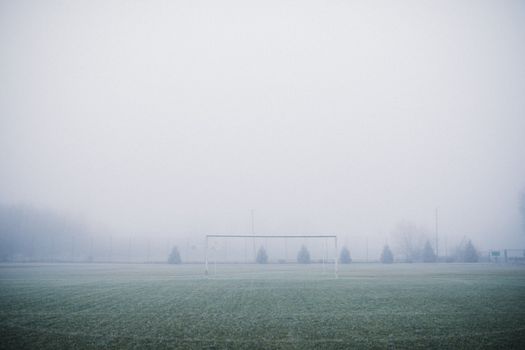 A foggy, frosty football field with low visibility creating a serene winter landscape.