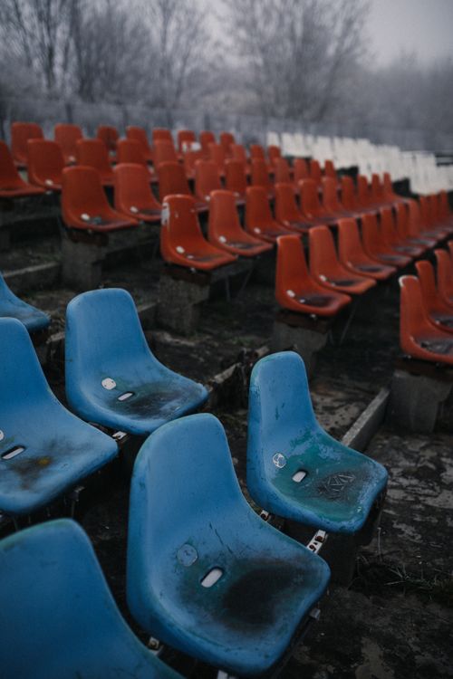 Free Abandoned and weathered colorful bleachers at an outdoor stadium under a cloudy winter sky. Stock Photo