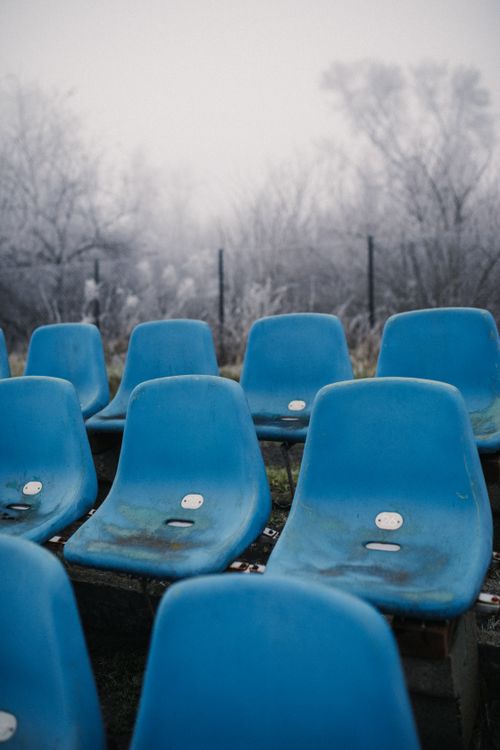 Free Empty blue chairs at foggy sportsground bleachers in winter. Stock Photo