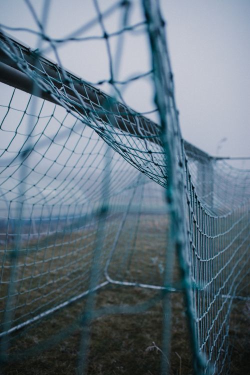 Free Close-up of a football goal net outdoors on a gloomy day, captures the misty atmosphere. Stock Photo