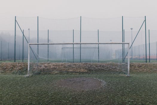Misty football field featuring a frosty goal post and fog enveloping the sports ground.