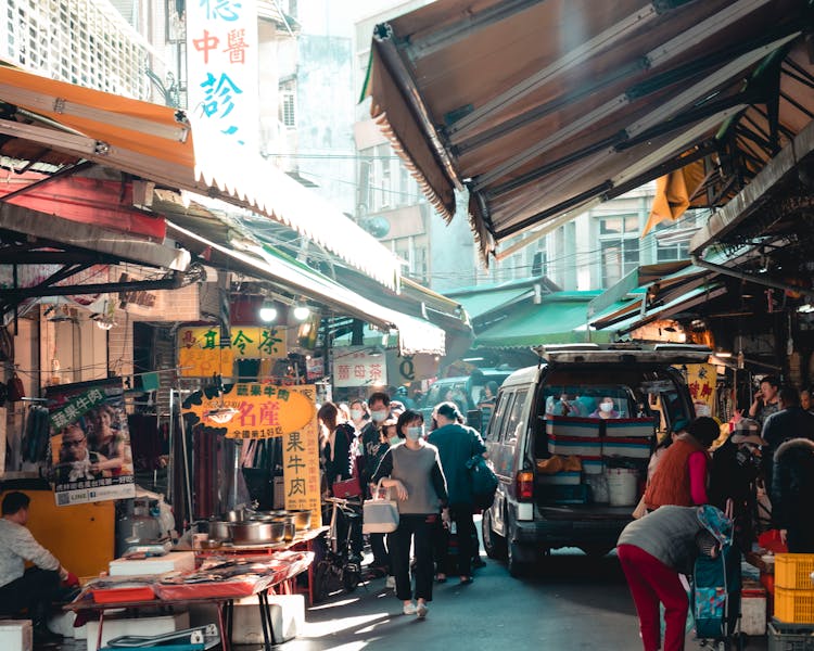 Unrecognizable Ethnic People Walking In Street Market In Sunlight