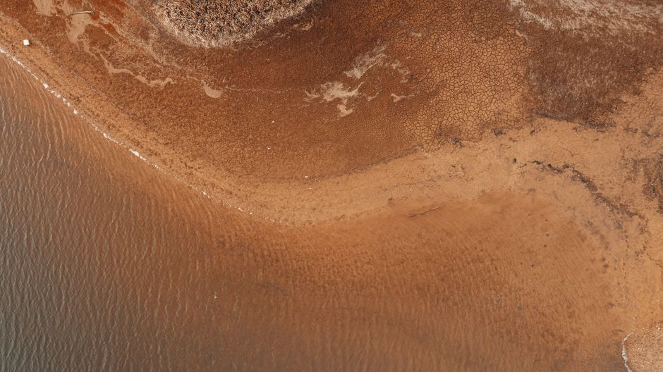Aerial view of textured backdrop representing pure sea water and brown shore in daylight