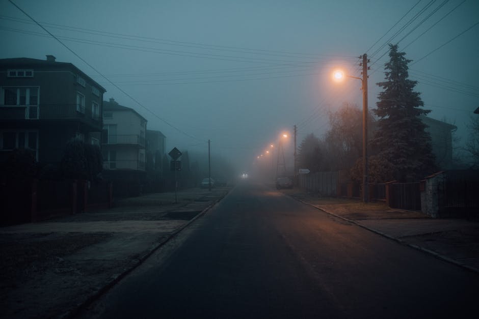 Misty night scene on a deserted road with glowing streetlights, capturing a moody atmosphere.