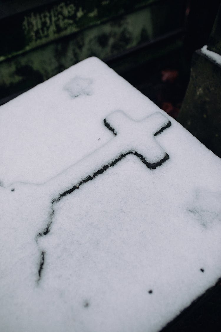 A Cross Over A Tomb Covered With Snow