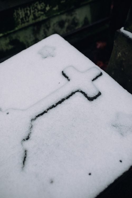 Free A close-up of a snow-covered cross on a cemetery tombstone in winter. Stock Photo