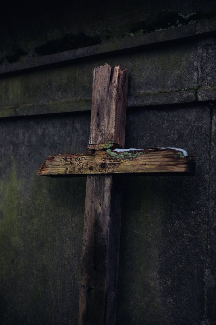 A Broken Wooden Crucifix Leaning On Concrete