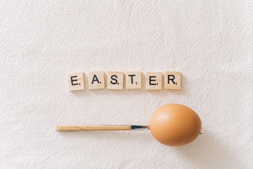 Free A creative Easter concept featuring a brown egg with Scrabble tiles spelling 'Easter.' Stock Photo