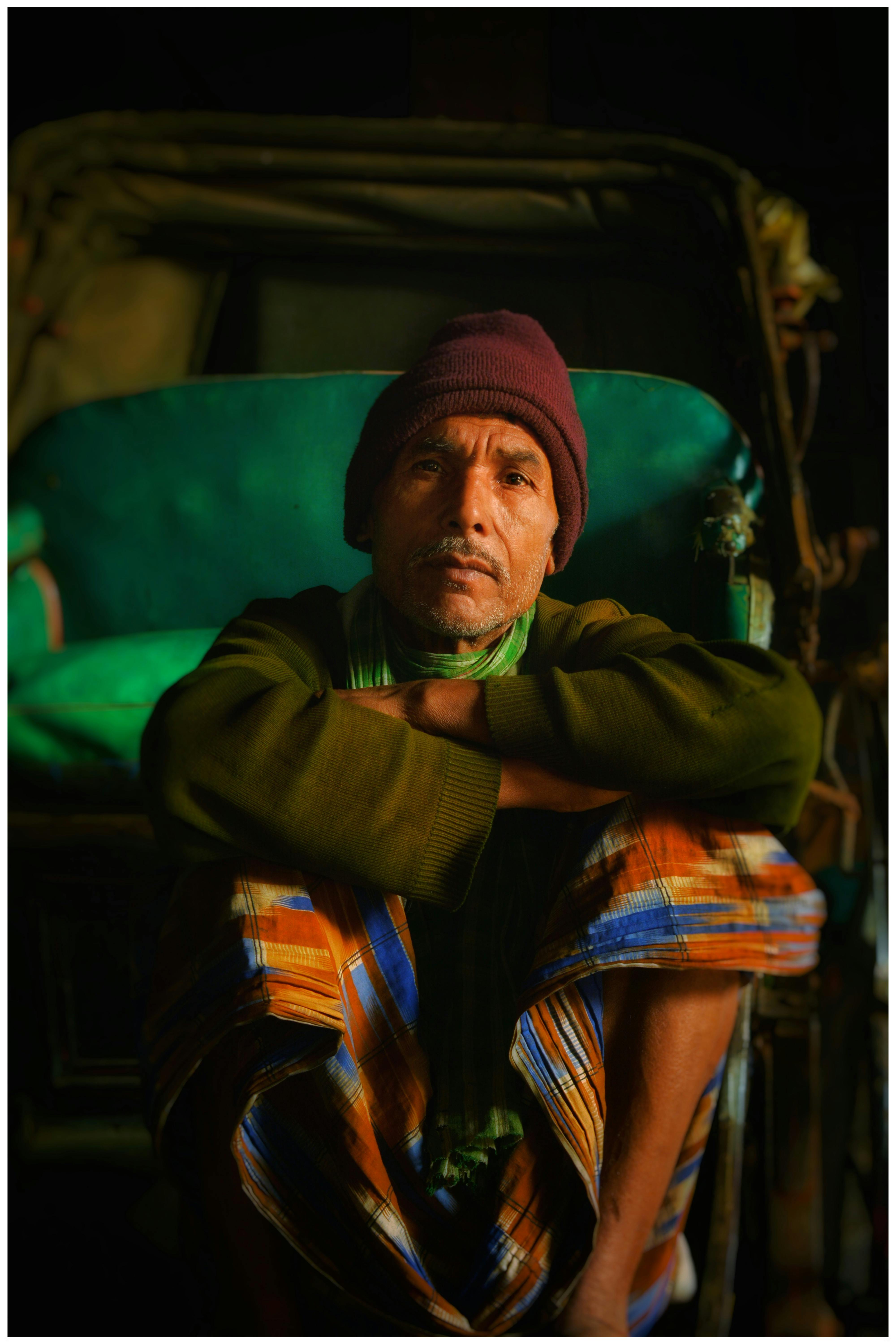 Elderly man sitting in a rickshaw at night in Kolkata, India, wearing warm clothing.