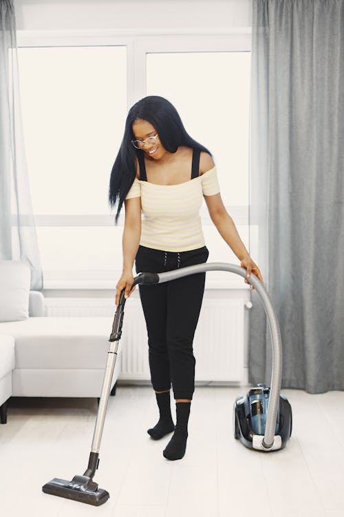 Free A Woman Using a Vacuum Cleaner to Clean the Floor Stock Photo