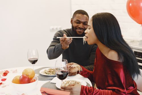 Free Couple enjoying a romantic dinner with wine and noodles, creating a special moment. Stock Photo