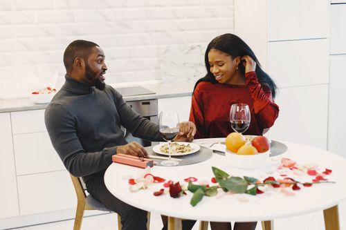 Free Couple enjoying a romantic dinner at home with wine and flowers. Stock Photo