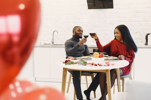 Free Couple enjoying a romantic indoor dinner with wine and roses. Stock Photo