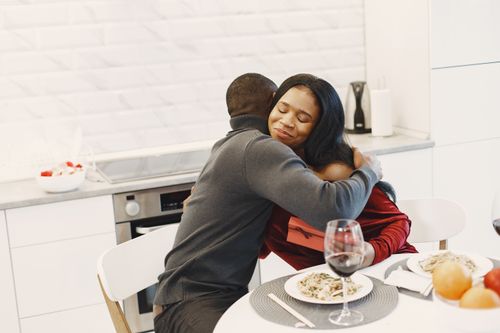 Free A couple sharing a warm embrace over a romantic dinner in a modern kitchen. Stock Photo
