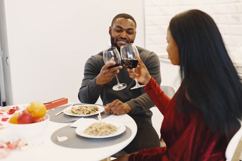Free Couple enjoying a romantic dinner with wine, celebrating togetherness indoors. Stock Photo