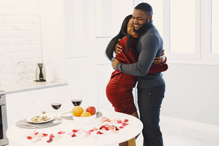 Man And Woman Hugging And Valentine Dinner With Wine On Table