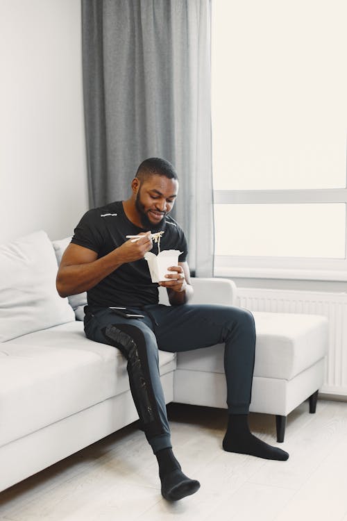 Man Sitting on Sofa While Eating