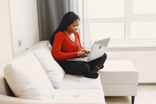 Woman Sitting on Sofa While Using a Laptop