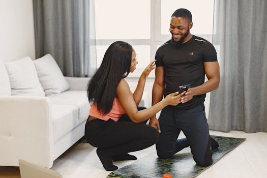 A couple enjoys a workout session indoors, using a smartphone for guidance.