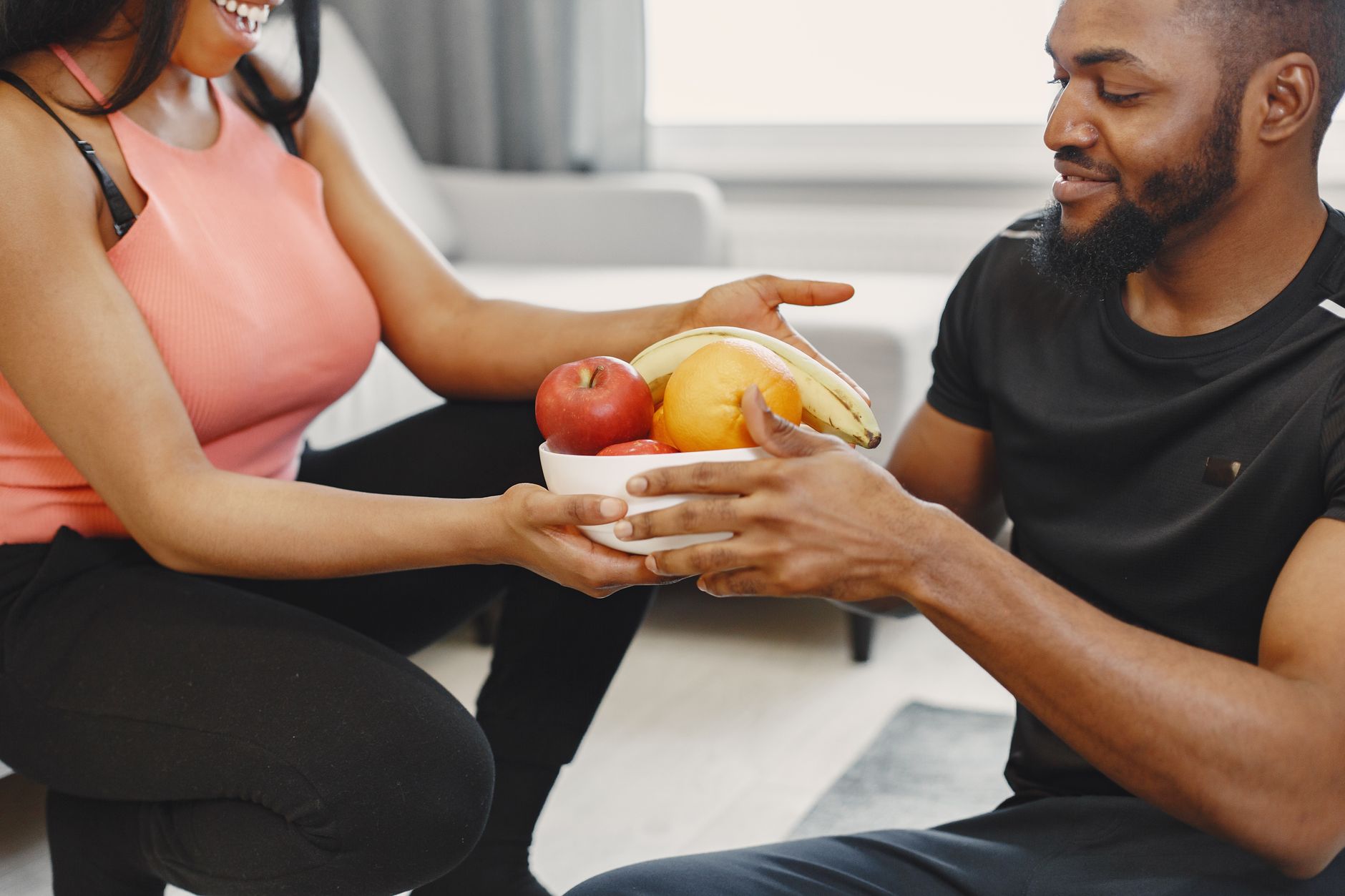 A happy couple enjoying fresh fruits together at home, promoting a healthy lifestyle.
