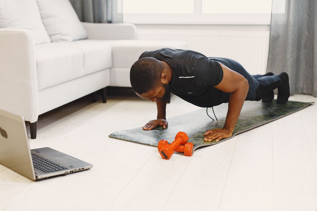 Man performing a push-up on a yoga mat in a modern living room, building strength at home with no equipment