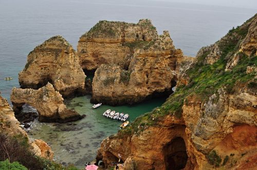 Free Stunning aerial view of rocky cliffs with boats docked in a serene ocean inlet. A perfect blend of nature's beauty. Stock Photo