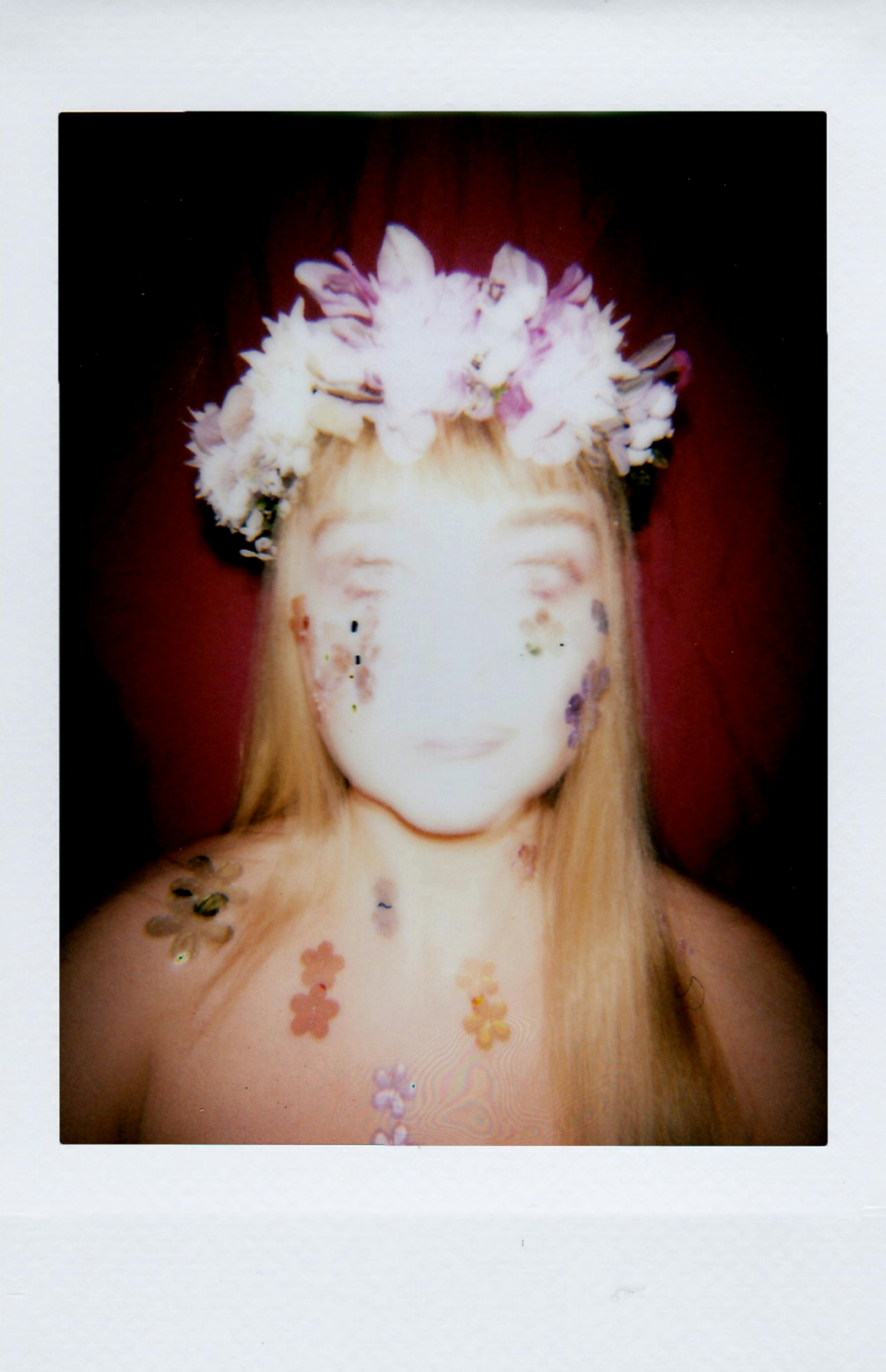 Artistic portrait of a woman with floral crown and stickers, captured in a soft, defocused style.