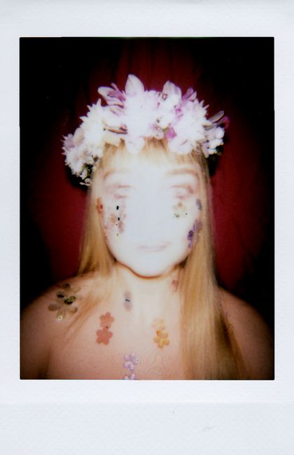 Artistic portrait of a woman with floral crown and stickers, captured in a soft, defocused style.