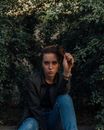 Young woman pouting lips sitting among green plants