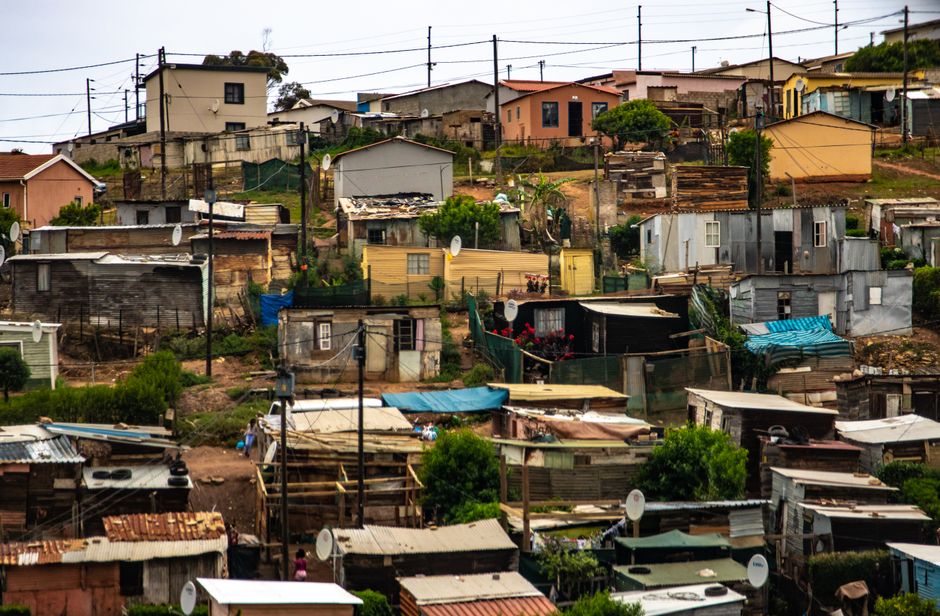 Colorful view of a shantytown with various houses and electric poles under an overcast sky.