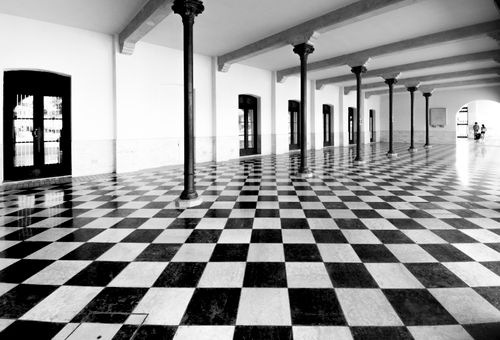 Free A striking black and white corridor with checkered flooring and classic columns. Stock Photo