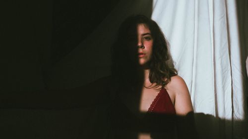 Free Artistic portrait of a woman in shadows with a moody atmosphere. Stock Photo