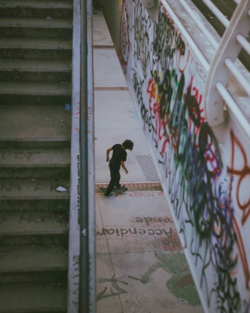 Free A skateboarder rides along a graffiti-covered alley beside a staircase, adding urban vibrancy. Stock Photo