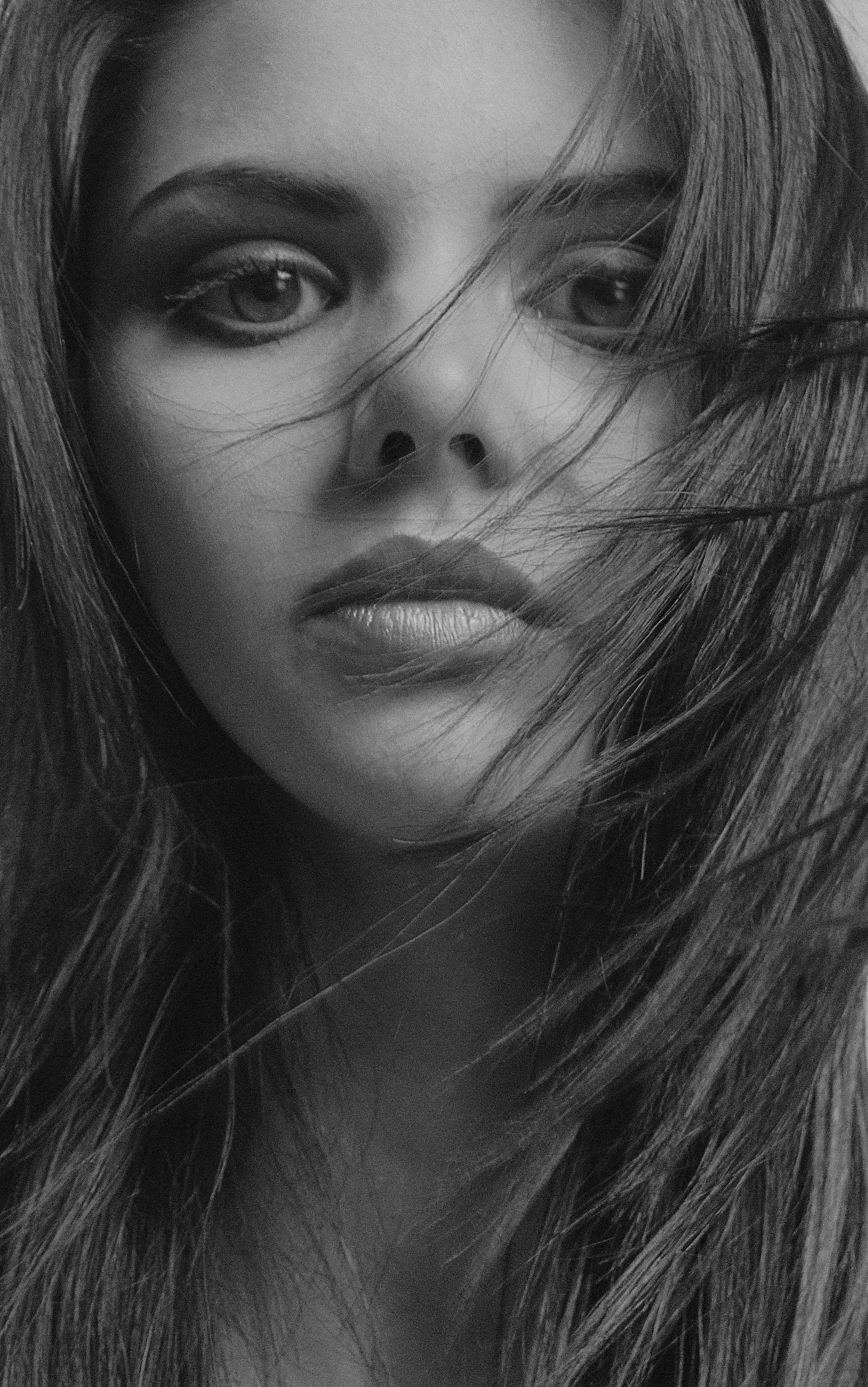 Captivating black and white portrait of a woman with flowing hair, conveying emotion and depth.