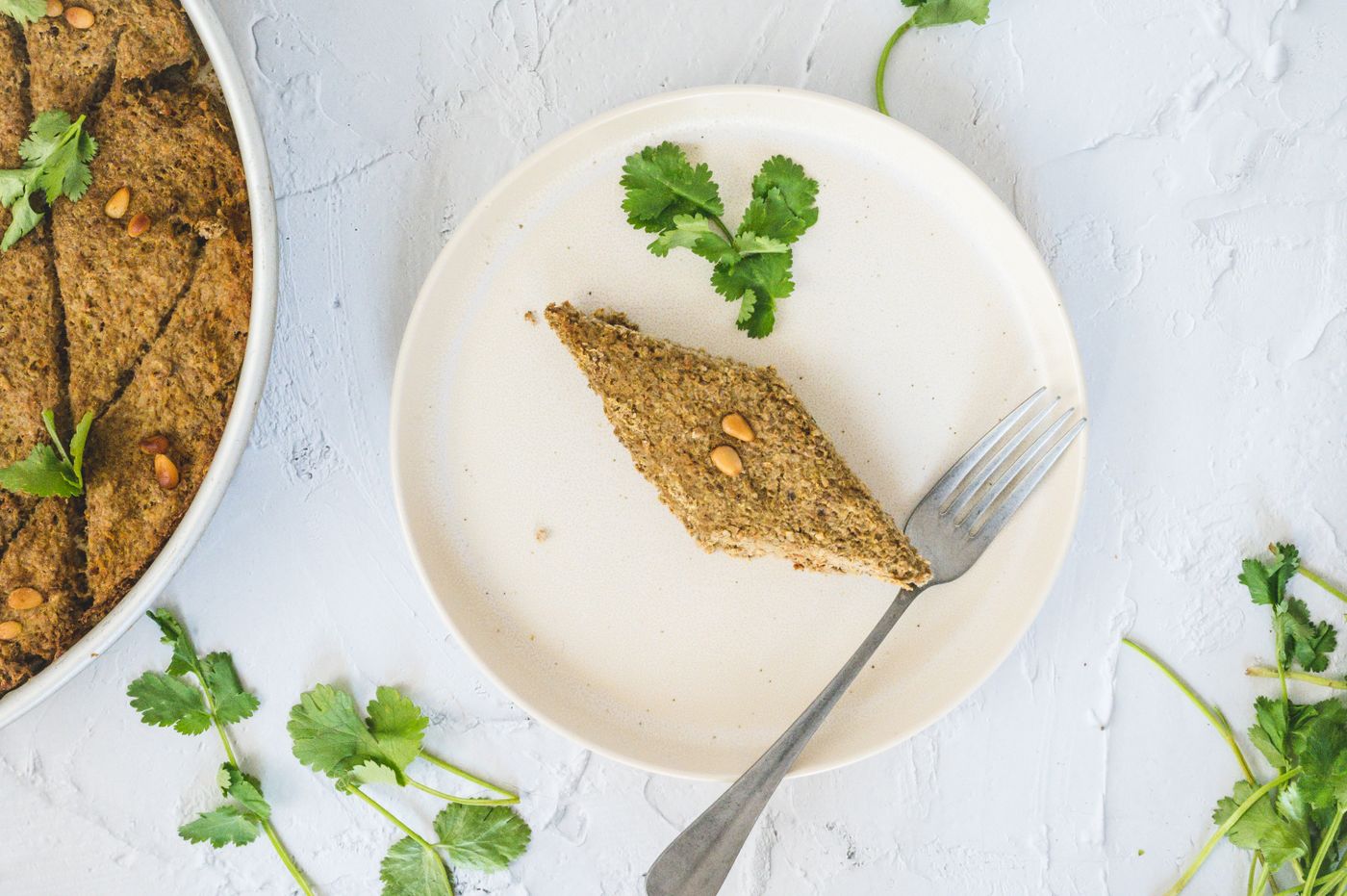 A slice of Middle Eastern kibbeh garnished with fresh herbs on a plate, perfect for gourmet food photography.