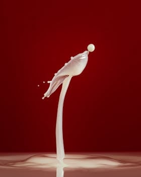 A striking studio capture of a dynamic milk splash against a deep red backdrop.