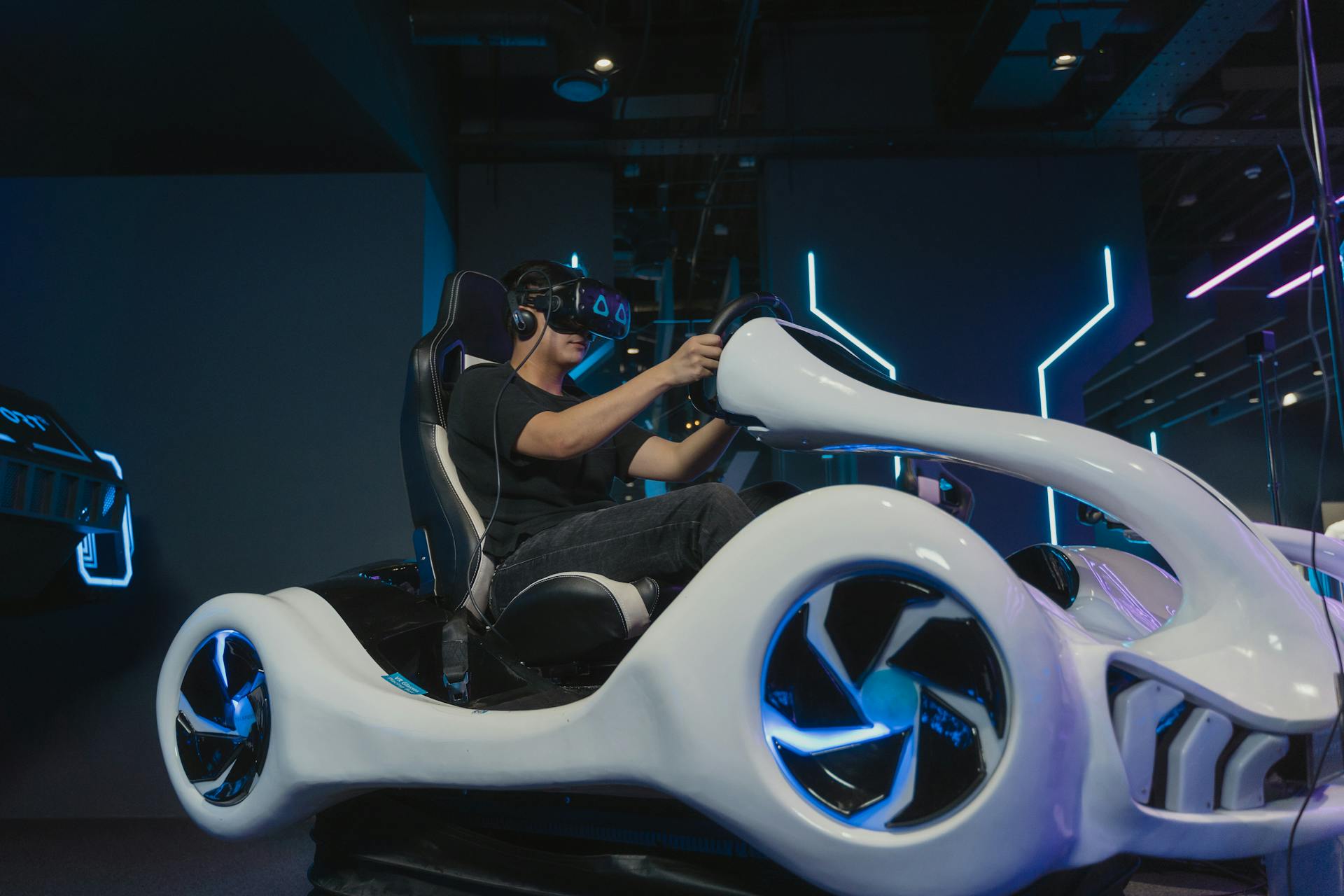 A young man engaging in a virtual reality driving simulation indoors with futuristic setup.