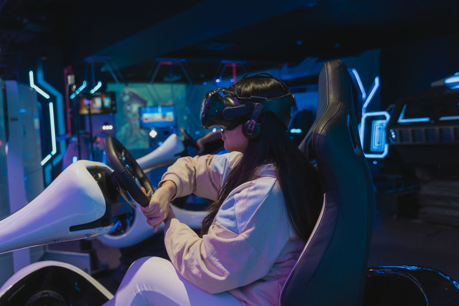 Young woman immersed in a virtual reality racing game in a futuristic setting.