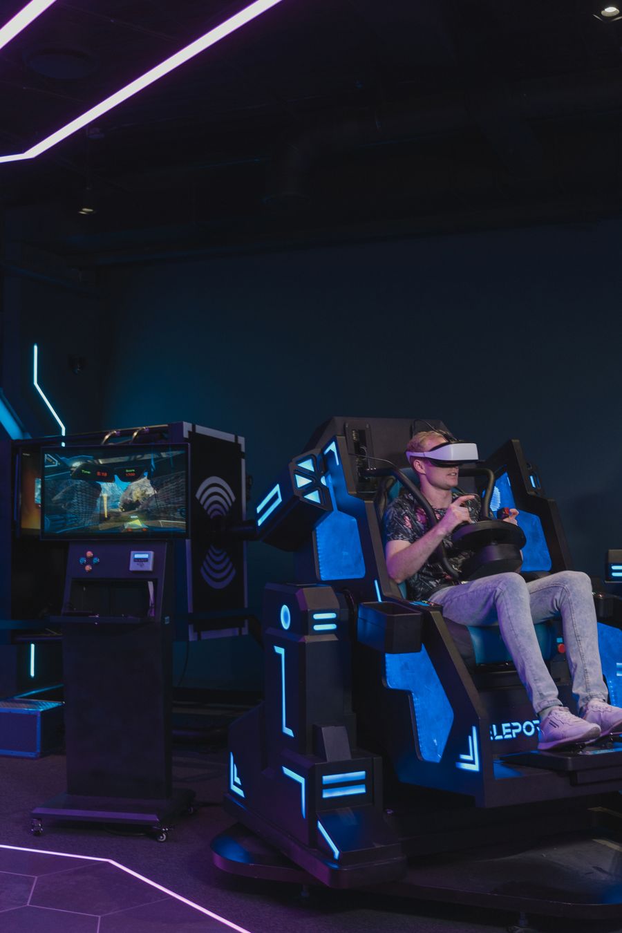 Speler met VR-headset in een neonverlichte arcade setup