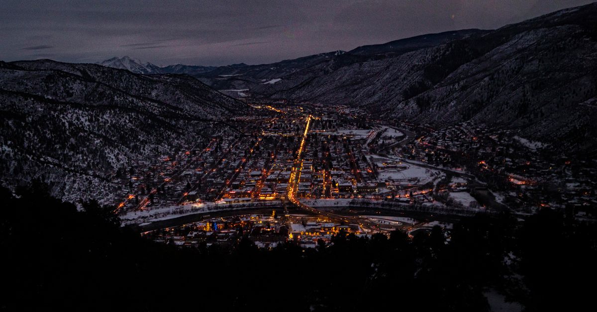 Captivating aerial night view of Glenwood Springs, CO in winter, highlighting urban lights.