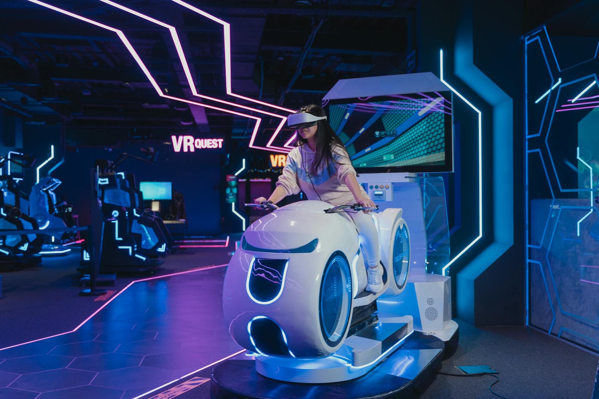 A woman immerses in a virtual reality arcade game, surrounded by neon lights and futuristic design.