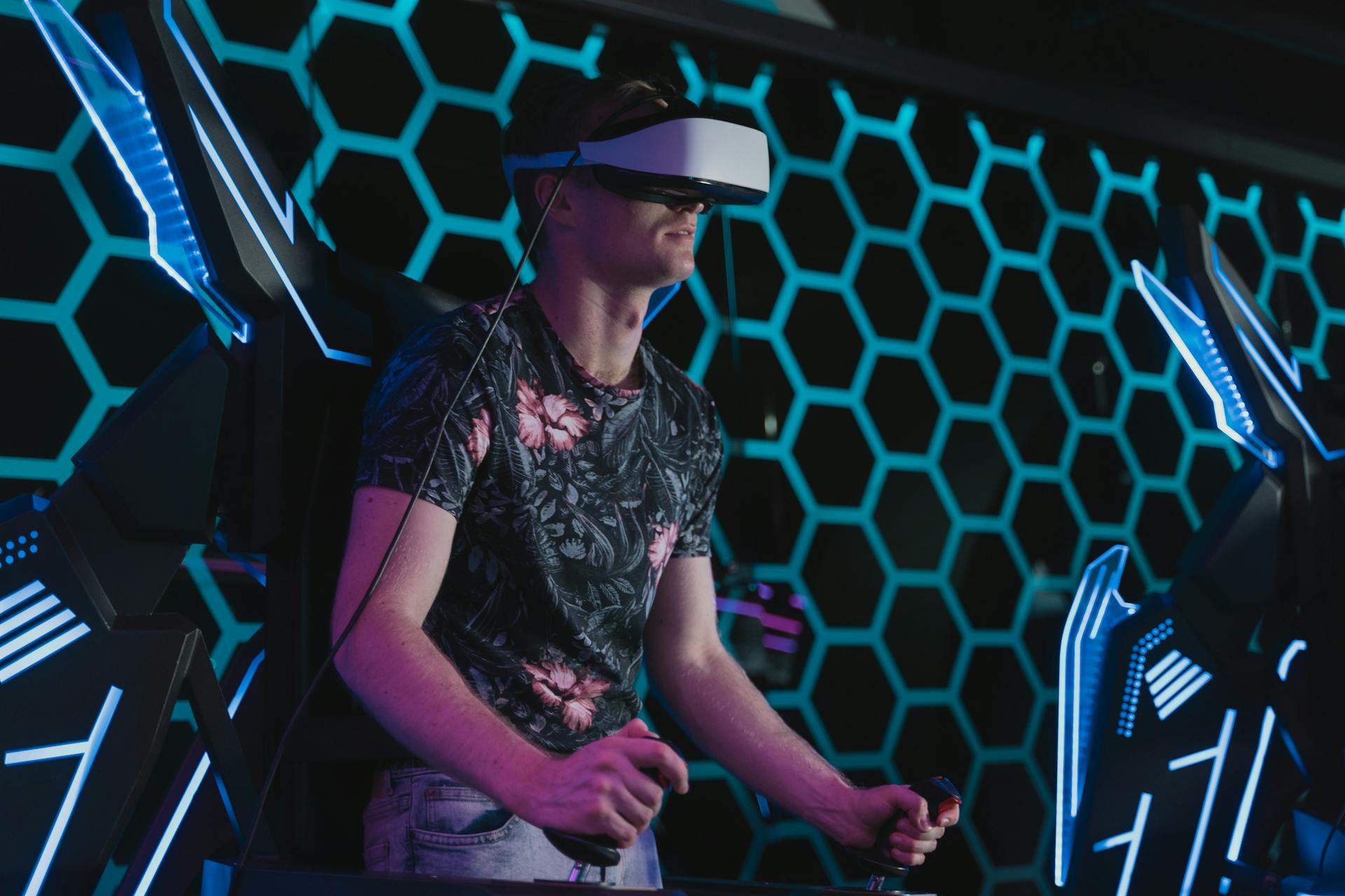 An adult male enjoying a virtual reality game in an arcade setting with futuristic elements.